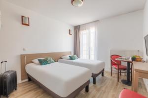 a hotel room with two beds and a table at Appart'City Classic Chalon sur Saone in Chalon-sur-Saône