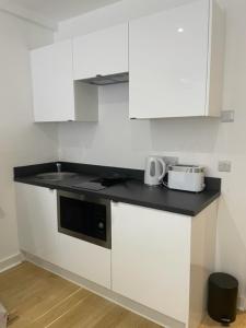 a kitchen with white cabinets and a black counter top at New 2A Soho Studios by Indigo Flats Sleeps 4 in London
