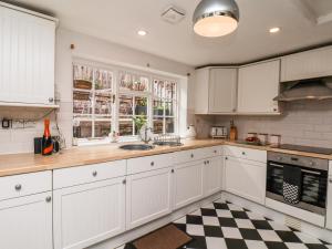 a kitchen with white cabinets and a checkered floor at Midships Cottage in Whitby