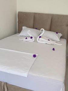 a bed with white sheets and purple flowers on it at Holliday Tivat in Peani