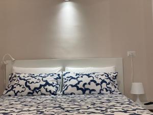 a bed with blue and white sheets and pillows at Appartamento al civico 16 in Licata