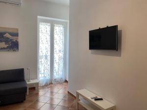 a living room with a couch and a television on the wall at Appartamento al civico 16 in Licata