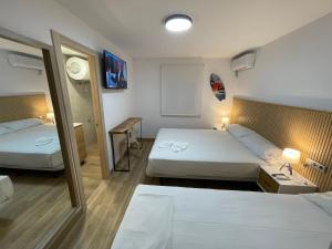 a hotel room with two beds and a mirror at Pinet Playa in Alicante
