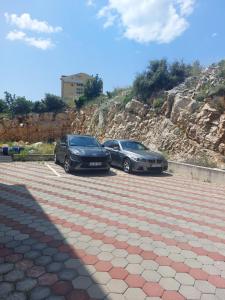zwei Autos auf einem Parkplatz neben einem Berg geparkt in der Unterkunft Vesna Meterize A2+1 in Šibenik