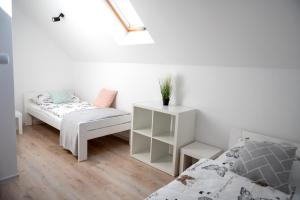 Habitación blanca con 2 camas y una mesita de noche en Emma Apartamenty, en Gostyń