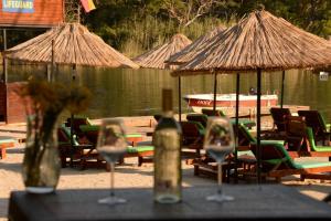 Green Pine Bungalows & Beach Luxury Concept في أولدينيس: طاولة مع كؤوس نبيذ وكراسي أمام البحيرة