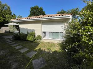 a small white house with a window in a yard at Entre bassin et forêt in La Teste-de-Buch