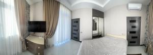 1 dormitorio con 1 cama, TV y espejo en Villa Novxani, en Baku