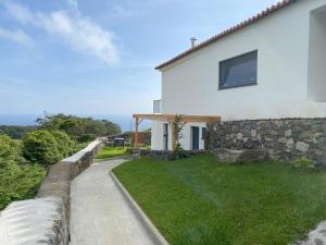 una casa blanca con una pared de piedra junto a un patio en LUZZ me - Casa das Doze Ribeiras, en Doze Ribeiras