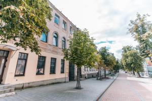 a street in front of a building with a tree at Rigas street cozy apartment, city centre in Daugavpils