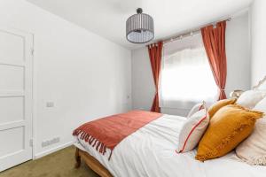a bedroom with a bed with orange curtains and a window at Serene 3BD Flat view of the Thames - Hammersmith in London
