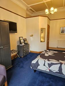 1 dormitorio con 1 cama, vestidor y TV en Smiths Guest House en Edimburgo