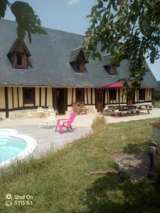 una casa con una silla rosa junto a una piscina en Longère les pieds dans l eau, en Saint-Philbert-sur-Risle