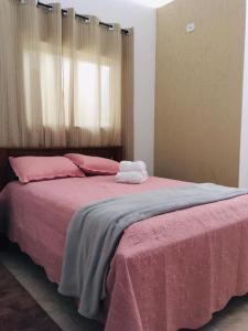 a bedroom with a large bed with pink sheets at Hospedagem Alto da Montanha in Cunha