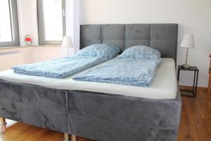 uma grande cama cinzenta com duas almofadas em Ferienwohnung Haus Knäppen Size M em Oelde