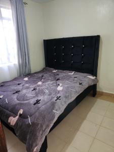 a bed with a black headboard with a blanket on it at Zuri Homes 2 in Keruguya