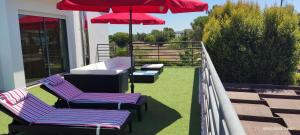 a balcony with two chairs and a red umbrella at Villa De Lux with pool in Quinta do Anjo