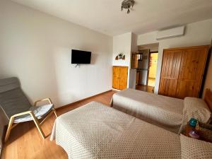 Cette chambre comprend un lit, une chaise et une télévision. dans l'établissement Apartamentos Sol y Luna 3000, à Peñíscola