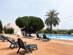 - une rangée de chaises assises à côté de la piscine dans l'établissement Apartamentos Sol y Luna 3000, à Peñíscola