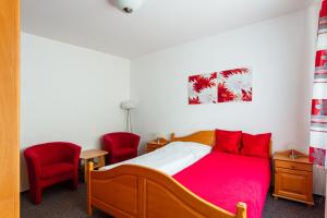 um quarto com uma cama e 2 cadeiras vermelhas em Penzion na Smetance em Zlín