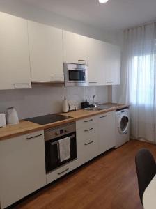La cuisine est équipée de placards blancs et d'un four avec plaques de cuisson. dans l'établissement Apartamento Vista Bella, à Madrid