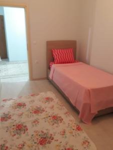 a bedroom with a bed with a red pillow and a rug at günlük aylık kralık daire in Arsin