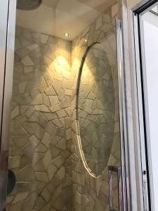 a shower with a glass door with a stone wall at MINA in Giglio Porto