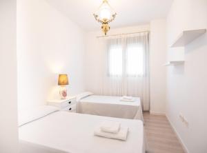 a white bedroom with two beds and a window at SibsSanlucar Manzanilla-Piscina-Terraza-BajoGuia-Playa-Centro in Sanlúcar de Barrameda