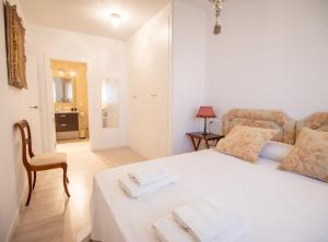a white bedroom with a white bed and a chair at SibsSanlucar Manzanilla-Piscina-Terraza-BajoGuia-Playa-Centro in Sanlúcar de Barrameda