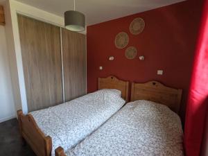 two twin beds in a bedroom with red walls at Oisans Chalet indépendant in Le Vert