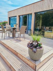 una terraza de madera con mesa, sillas y una maceta en Penzion Včelařský Dvůr, en Lednice