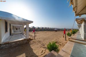 a row of huts on a sandy beach with flags at Shama Desert Luxury Camp & Resort in Jaisalmer