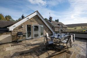 a stone house with a table and chairs on a patio at Roundhill Coach House in Healey