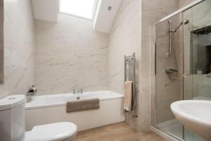 a bathroom with a tub and a toilet and a sink at Roundhill Coach House in Healey +18 photos
