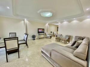 Una sala de estar con un sofá, una mesa y un televisor. en A201 - Vista Mar | 3 Quartos c/ Wifi e Churrasqueira, en Samaritá