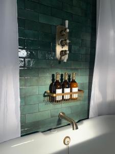 a bathroom with bottles of wine on a shelf next to a tub at Cosy Cottage in Lechlade in Lechlade