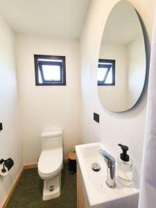 La salle de bains est pourvue de toilettes blanches et d'un miroir. dans l'établissement Exclusiva Cabin en tranquilo campo a orillas del lago con vista a volcanes - hot tub privado, à Frutillar