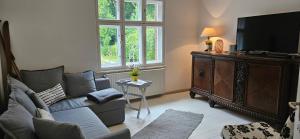 ein Wohnzimmer mit einem Sofa und einem Flachbild-TV in der Unterkunft Kleines Landhaus am Wald Bad Saarow in Bad Saarow