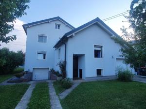 a white house with a garage and a yard at Ferienwohnung Nussbaumblick in Ottensheim