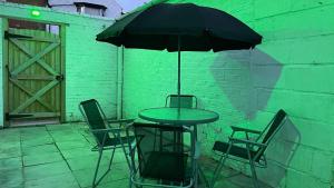 a table and chairs with an umbrella on a patio at Top Quality Modern Southsea Garden Apartment Sleeps 4 People in Portsmouth