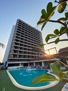 a hotel with a swimming pool in front of a building at First Pacific Hotel and Convention in Pattaya Central