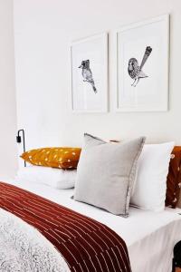 a bed with white pillows and pictures on the wall at Mistwood - Pet Friendly in Mount Macedon