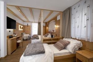 a bedroom with two beds and a desk and a room at Albergo Miravalle Fai della Paganella in Fai della Paganella