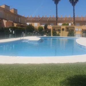 una grande piscina blu di fronte a un edificio di Acogedor chalet adosado en playas de Isla Cristina a La Redondela
