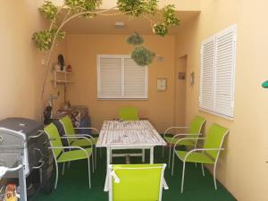 uma mesa e cadeiras verdes num quarto com um fogão em Acogedor chalet adosado en playas de Isla Cristina em La Redondela