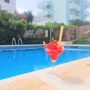 a drink in a martini glass next to a pool at Tabbu ibiza apartments in Playa d'en Bossa