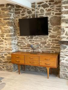a wooden dresser with a television on a stone wall at Number Eleven, Brixham in Brixham