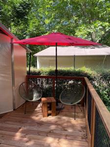 two chairs and a red umbrella on a deck at Camping le Pré Morjal in Ispagnac