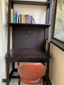 a desk with a chair and a book shelf with books at Dominos 1 BHK Apartment, Near Carter Road by Connket Homes in Mumbai