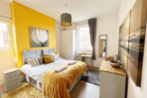 a bedroom with a bed and a yellow wall at St Helens House in Portsmouth